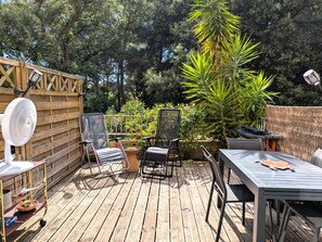 Eine Holzterrasse mit Gartenmöbeln, einem Ventilator und einem Tisch.