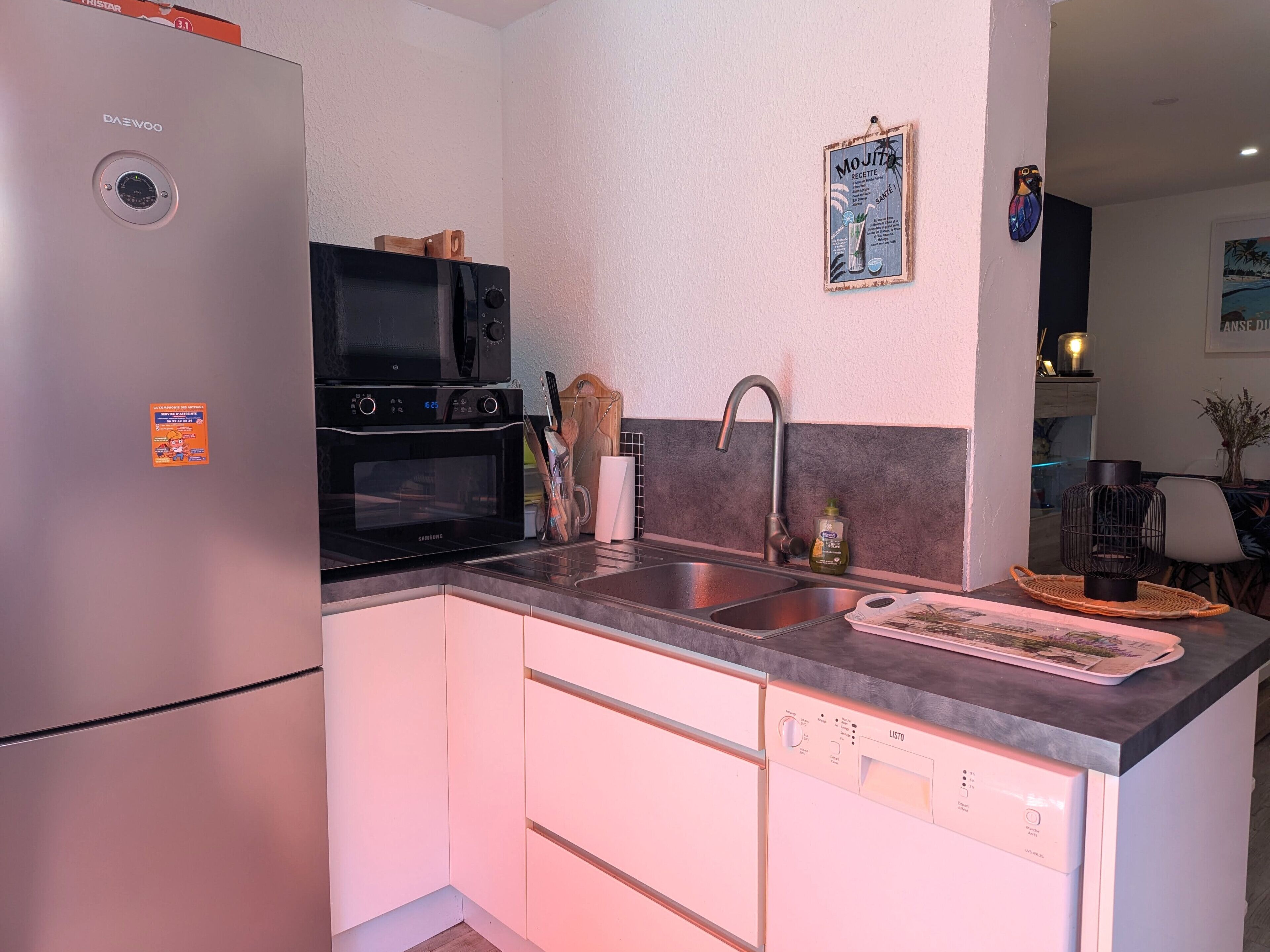 A kitchen with a refrigerator, microwave, oven, sink, and dishwasher.