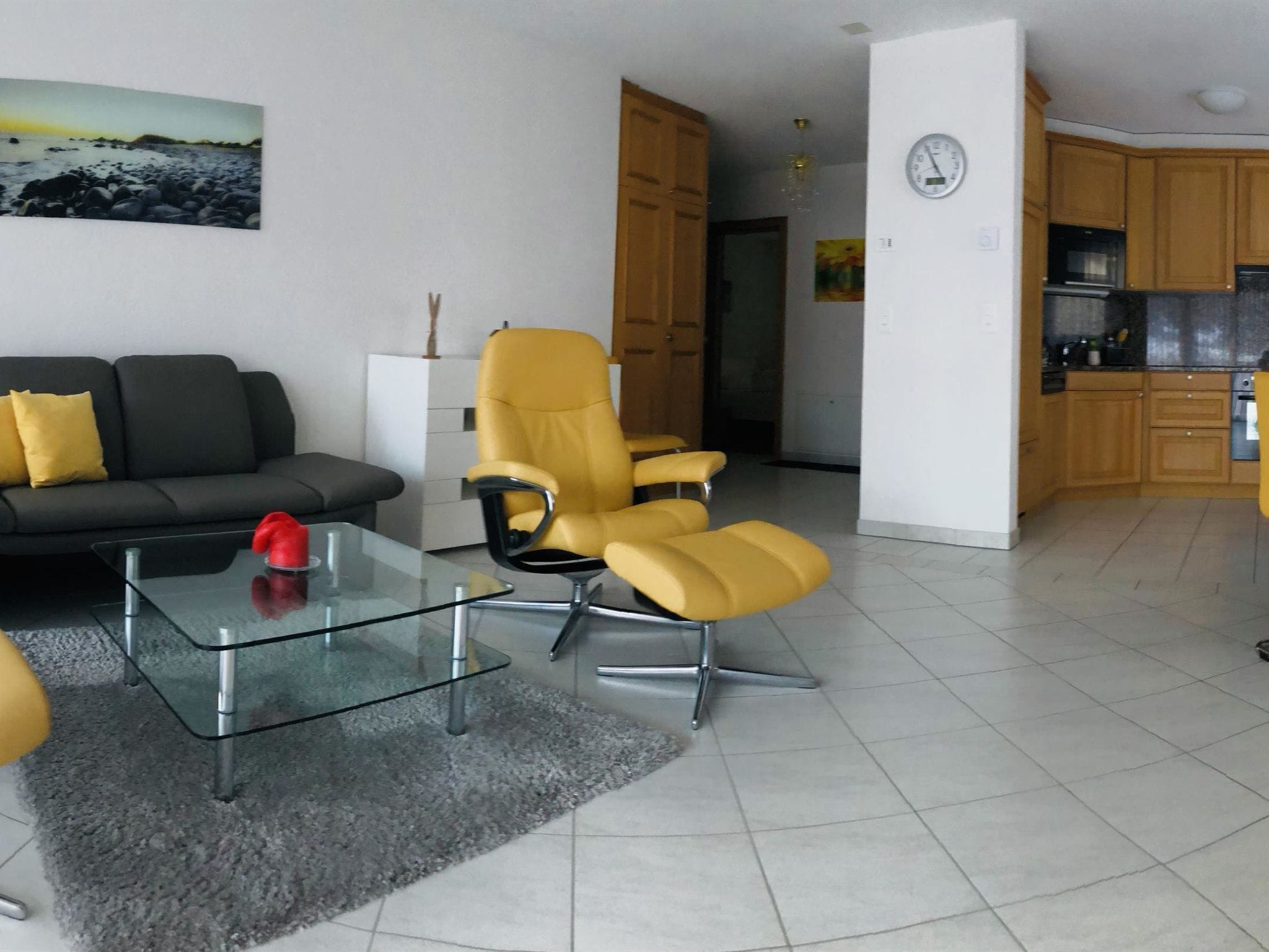 Uma sala de estar moderna com um sofá, uma mesa de centro de vidro e duas poltronas amarelas.