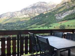 A terrace with a table and chairs, overlooking a mountainous landscape. - Edelweiss B 23 # 4-bed apartment, Dusche, WC 4-bed apartment, Dusche, WC by Interhome (Leukerbad)