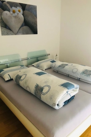 A bed with a patterned blanket and pillows, a glass headboard, and a wall-mounted picture. - Edelweiss B 23 # 4-bed apartment, Dusche, WC 4-bed apartment, Dusche, WC by Interhome (Leukerbad)