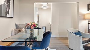 Un comedor moderno con una mesa de vidrio, sillas azules y un jarrón con flores.