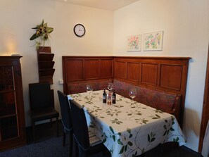 A dining area with a table set for two, a clock on the wall, and two framed floral paintings. - Salve 3 # 4-bed apartment, Dusche, WC 4-Bettwohnung, Dusche, WC by Interhome (Leukerbad)