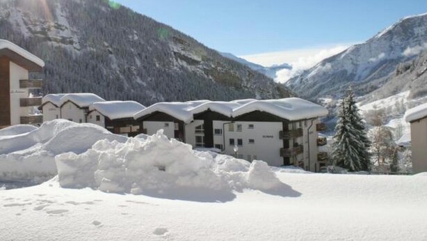 A snow-covered mountain resort with chalet-style buildings, a clear sky, and a sun shining. - Salve 3 # 4-bed apartment, Dusche, WC 4-Bettwohnung, Dusche, WC by Interhome (Leukerbad)
