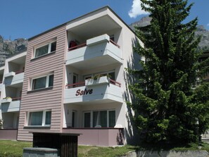 Ein mehrstöckiges Gebäude mit Balkonen, einem Schild mit der Aufschrift 'Salve' und einem großen Baum im Vordergrund.