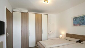 A hotel room with a bed, bedside table, lamp, wardrobe, and a painting on the wall. - Salve 3 # 4-bed apartment, Dusche, WC 4-Bettwohnung, Dusche, WC by Interhome (Leukerbad)