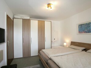 Ein Hotelzimmer mit Bett, Nachttisch, Lampe, Kleiderschrank und einem Bild an der Wand.