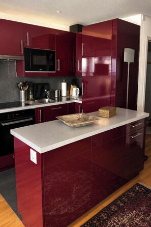 A modern kitchen with dark cabinetry, a microwave, and a built-in oven. - Majesta Leukerbad # 2-bed apartment, Dusche, WC by Interhome (Leukerbad)