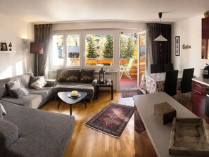 En moderne stue med en sofa, et sofabord og et spiseområde med stole og et bord.