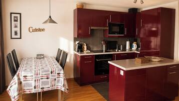 A compact kitchen with a dining table, chairs, a microwave, and a coffee maker.