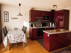 Una cucina compatta con tavolo, sedie, forno a microonde e macchina del caffè.