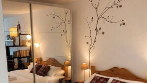 Una habitación de hotel con una cama grande, un espejo y una mesita de noche con lámpara.
