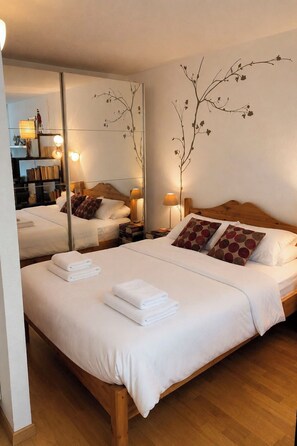 A hotel room with a large bed, a mirror, and a bedside table with a lamp. - Majesta Leukerbad # 2-bed apartment, Dusche, WC by Interhome (Leukerbad)