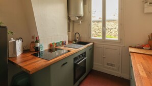 A kitchen with a wooden countertop, a sink, a stove, and a window with a view. - Spacious apartment right by Clichy Park (Paris)