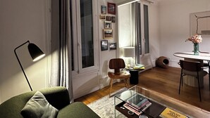 A modern living room with a sofa, coffee table, and dining area. - Spacious apartment right by Clichy Park (Paris)