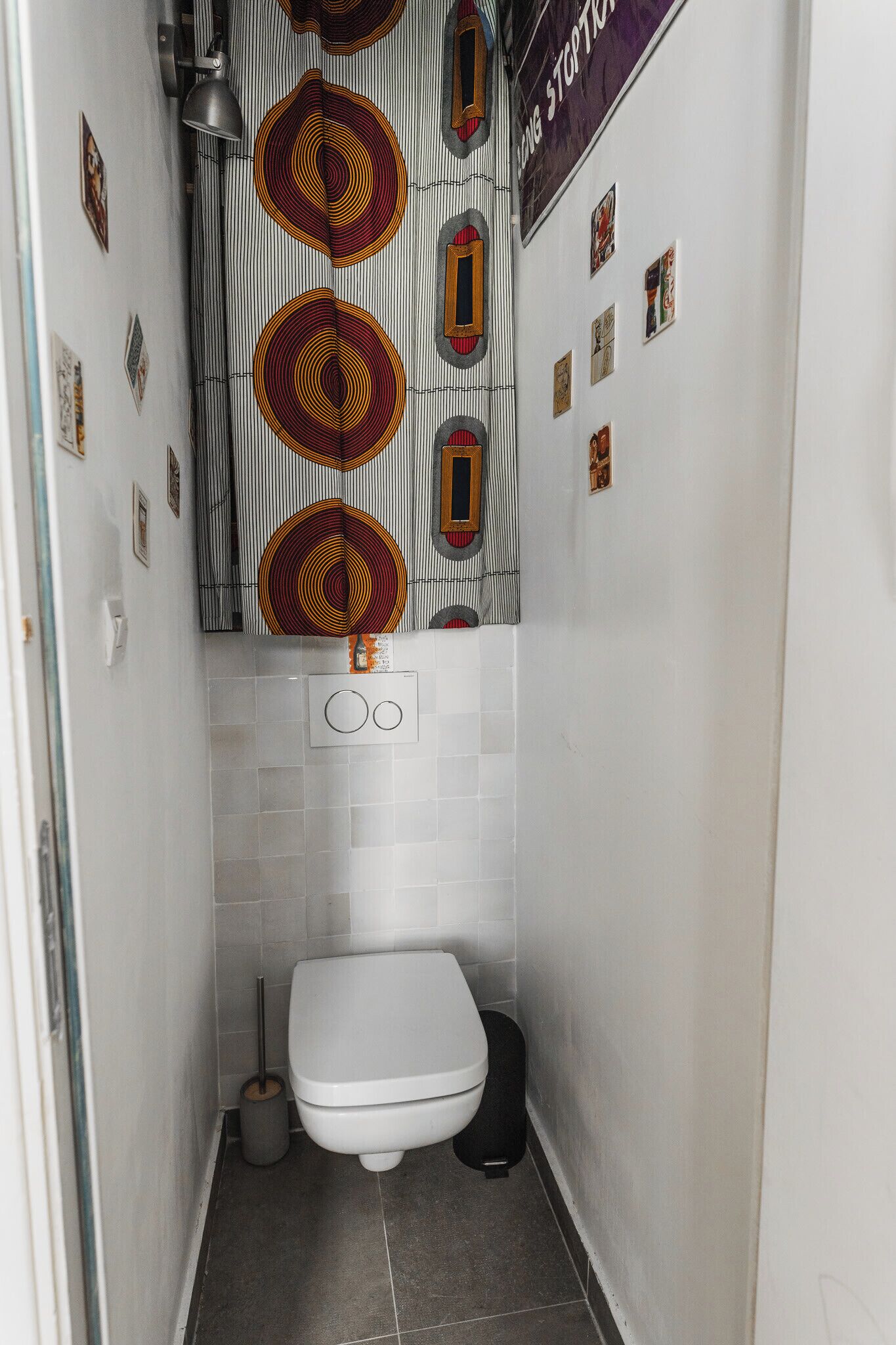 A narrow bathroom with a white toilet, a black bidet, and a wall-mounted towel rack.