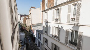 A narrow urban street with buildings featuring shutters and balconies. - Nice Apartment Near Buttes Chaumont (Paris)