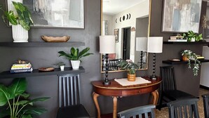 A modern living room with a large mirror, two chairs, a small table with a lamp, and decorative plants. - Sunset Villa Sleeps 10 Near Beach & SJU 4 bedroom Family House (Carolina)