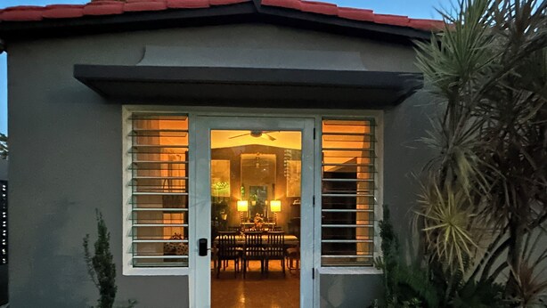 A building with a door and windows, a patio area with chairs, and potted plants. - Sunset Villa Sleeps 10 Near Beach & SJU 4 bedroom Family House (Carolina)