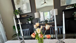 A dining table with a glass top, surrounded by chairs, a vase with flowers, and two candle holders. - Sunset Villa Sleeps 10 Near Beach & SJU 4 bedroom Family House (Carolina)