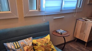 En blå sofa med mønstrede puder, et rundt bord med en bog og et træskab.