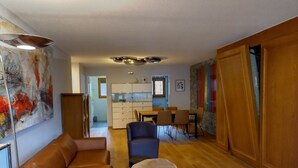 Ett modernt vardagsrum med en soffa, ett runt soffbord och en matplats med stolar och ett bord.