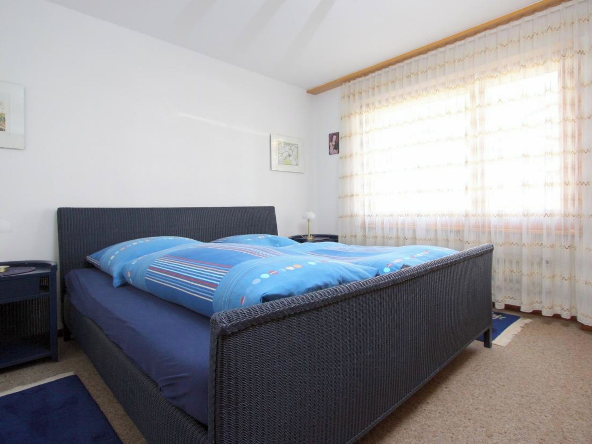 Una camera da letto con un letto singolo, un comodino, una lampada e una finestra con tende.