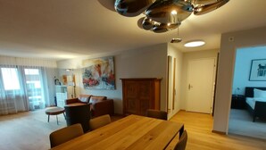 Ett rymligt vardagsrum med ett matbord i trä, en soffa och en stor, abstrakt tavla på väggen.