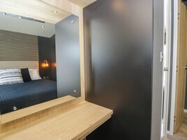 Un dormitorio moderno con cama, mesita de noche y un espejo que refleja la habitación.