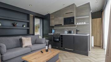 A modern kitchen with built-in appliances, a grey sofa, and a wooden coffee table.