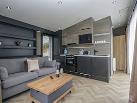Una cocina moderna con electrodomésticos integrados, un sofá gris y una mesa de centro de madera.