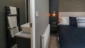 Un baño moderno con lavamanos blanco, toallero y radiador.