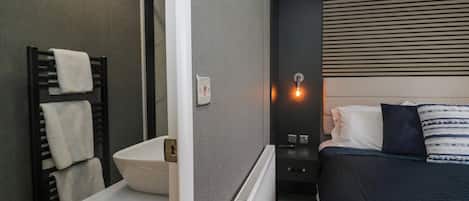 A modern bathroom with a white sink, towel rack, and a radiator.