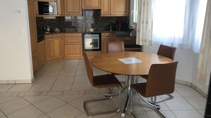 Eine Küche mit Holzausstattung, Backofen, Mikrowelle und einem Esstisch mit Stühlen.