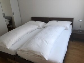 Ein Doppelbett mit weißer Bettwäsche in einem Hotelzimmer.