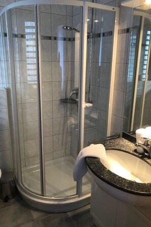 Une salle de bain moderne avec une douche à parois de verre, un lavabo blanc et un miroir.