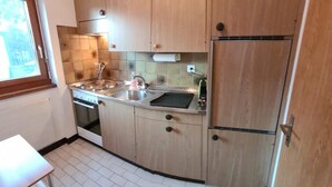 Een compacte keuken met houten kastjes, een roestvrijstalen spoelbak en een ingebouwde oven.