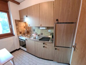 A compact kitchen with wooden cabinets, a stainless steel sink, and a built-in oven. - Arca 2 # 5-bed apartment, Bad, WC 5-bed apartment, Bad, WC by Interhome (Leukerbad)
