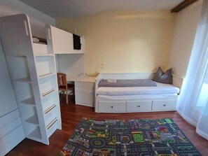 A bedroom with a bed, a desk, a chair, a wardrobe, and a colorful rug. - Arca 2 # 5-bed apartment, Bad, WC 5-bed apartment, Bad, WC by Interhome (Leukerbad)