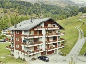 A multi-story chalet with balconies, set in a mountainous area with a road nearby. - Arca 2 # 5-bed apartment, Bad, WC 5-bed apartment, Bad, WC by Interhome (Leukerbad)