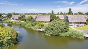 A riverside property with thatched-roof cottages, a dock, and lush greenery. - Romantic Villa for 2-guests With Sauna, Makkum (Makkum)