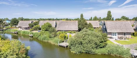 A riverside property with thatched-roof cottages, a dock, and lush greenery.