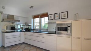 A kitchen with white cabinets, a microwave, and a window with blinds. - Romantic Villa for 2-guests With Sauna, Makkum (Makkum)
