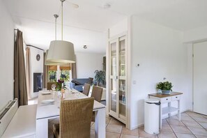 Ein Essbereich mit einem für zwei Personen gedecktem Tisch, einer Hängelampe und Blick in das Wohnzimmer.