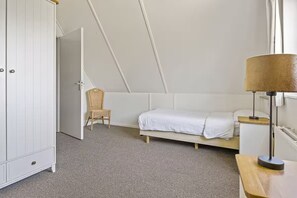Ein Schlafzimmer mit Bett, Stuhl, Kleiderschrank und Lampe.