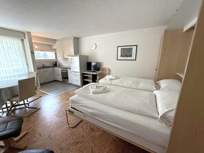 A compact hotel room with a bed, a desk, a chair, a television, and a kitchenette. - Fortuna 118 # 2-bed apartment, Dusche, WC 2-Bettwohnung, Dusche, WC by Interhome (Leukerbad)