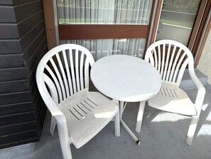 A small outdoor seating area with two white plastic chairs and a round table. - Fortuna 118 # 2-bed apartment, Dusche, WC 2-Bettwohnung, Dusche, WC by Interhome (Leukerbad)