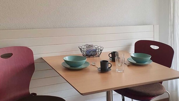 Ett matbord med två turkosa skålar, en svart mugg och ett glas vatten.