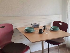 A dining table with two teal bowls, a black mug, and a glass of water. - Fortuna 116 # 2-bed apartment, Dusche, WC 2-Bettwohnung, Dusche, WC by Interhome (Leukerbad)