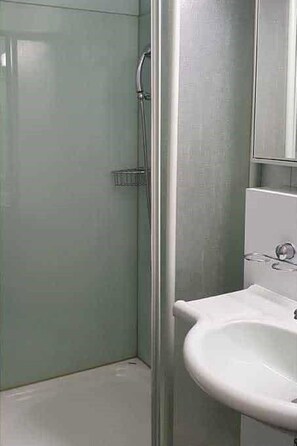 Ein Badezimmer mit Duschkabine, Waschbecken und Spiegel.